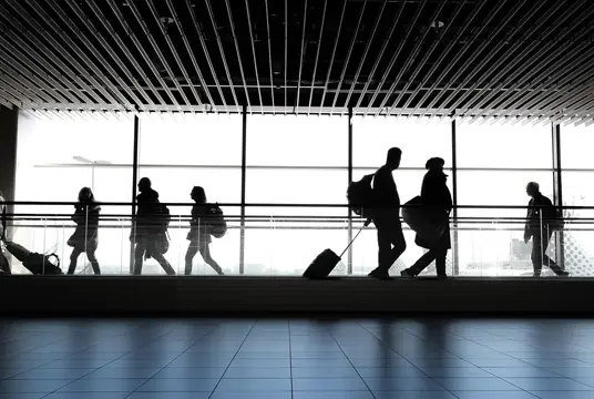 Människor på en flygplats som ser ut att vara på väg att resa eller precis kommit hem.