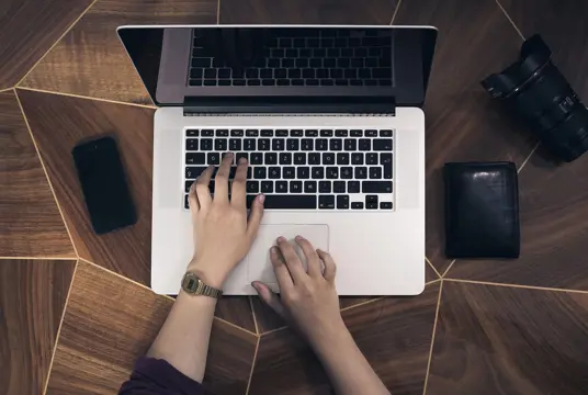 En laptop ståendes på ett designat ekbord.