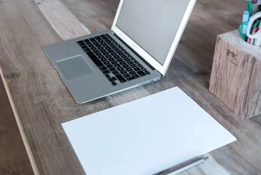 En laptop ståendes på ett skrivbord i rustikt trädslag.
