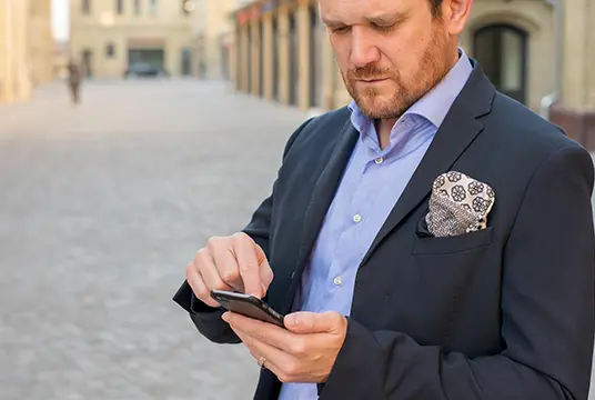 Man klädd i kostym surfar på mobilen.