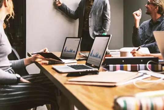 En grupp människor runt ett mötesbord som får budgeten presenterad.